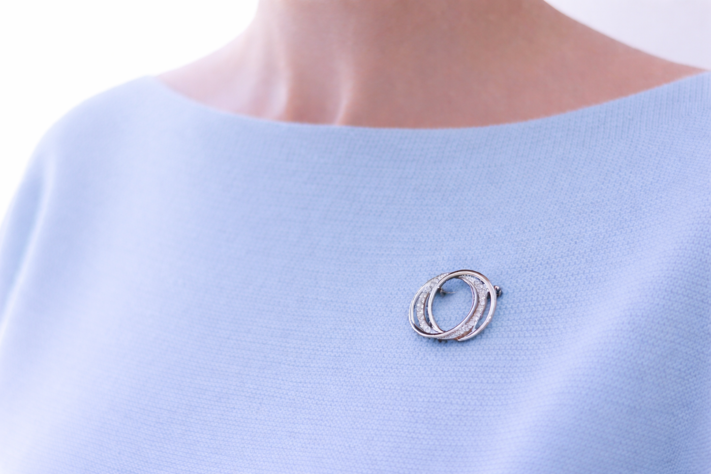 Silver brooch on a light blue garment