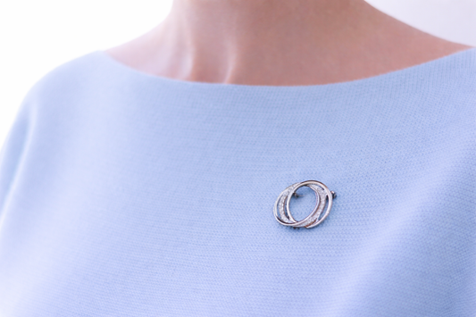 Silver brooch on a light blue garment