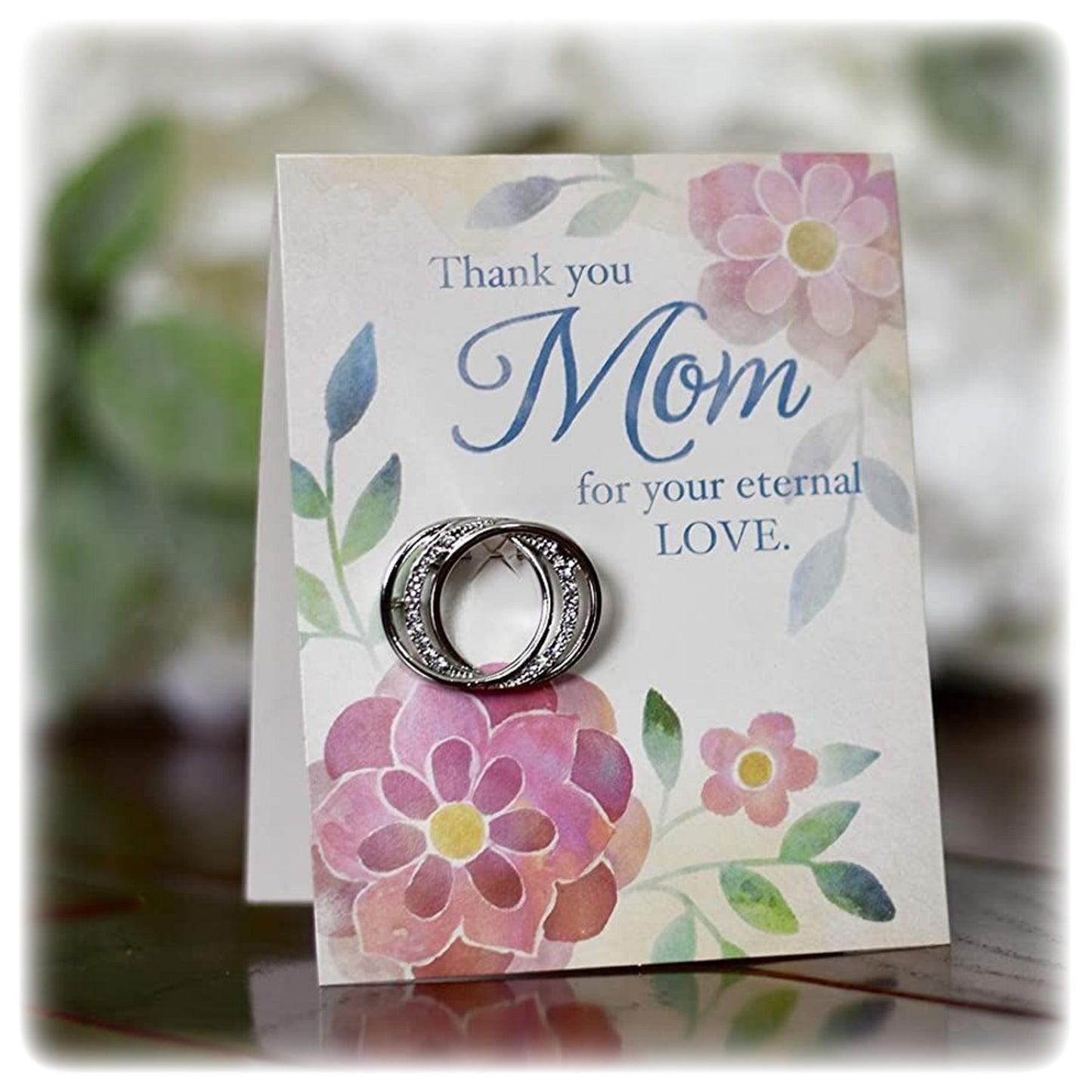 A scarf pin with a floral design and a thank you message to mom, presented on a card.