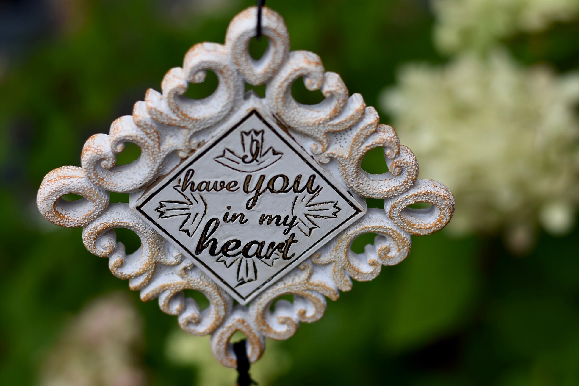 Close-up of memorial wind chime tubes engraved with “So until our heavenly reunion, I have you in my heart”